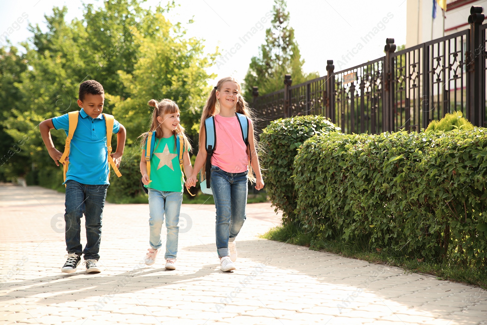 Photo of Cute little children with backpacks going to school