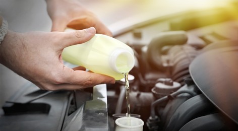 Image of Man filling car radiator with antifreeze outdoors, closeup