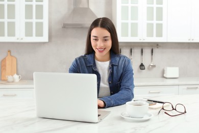 Home workplace. Woman working on laptop at marble desk in kitchen