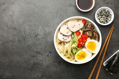 Photo of Delicious ramen with meat in bowl and ingredients on grey textured table, flat lay. Space for text. Noodle soup