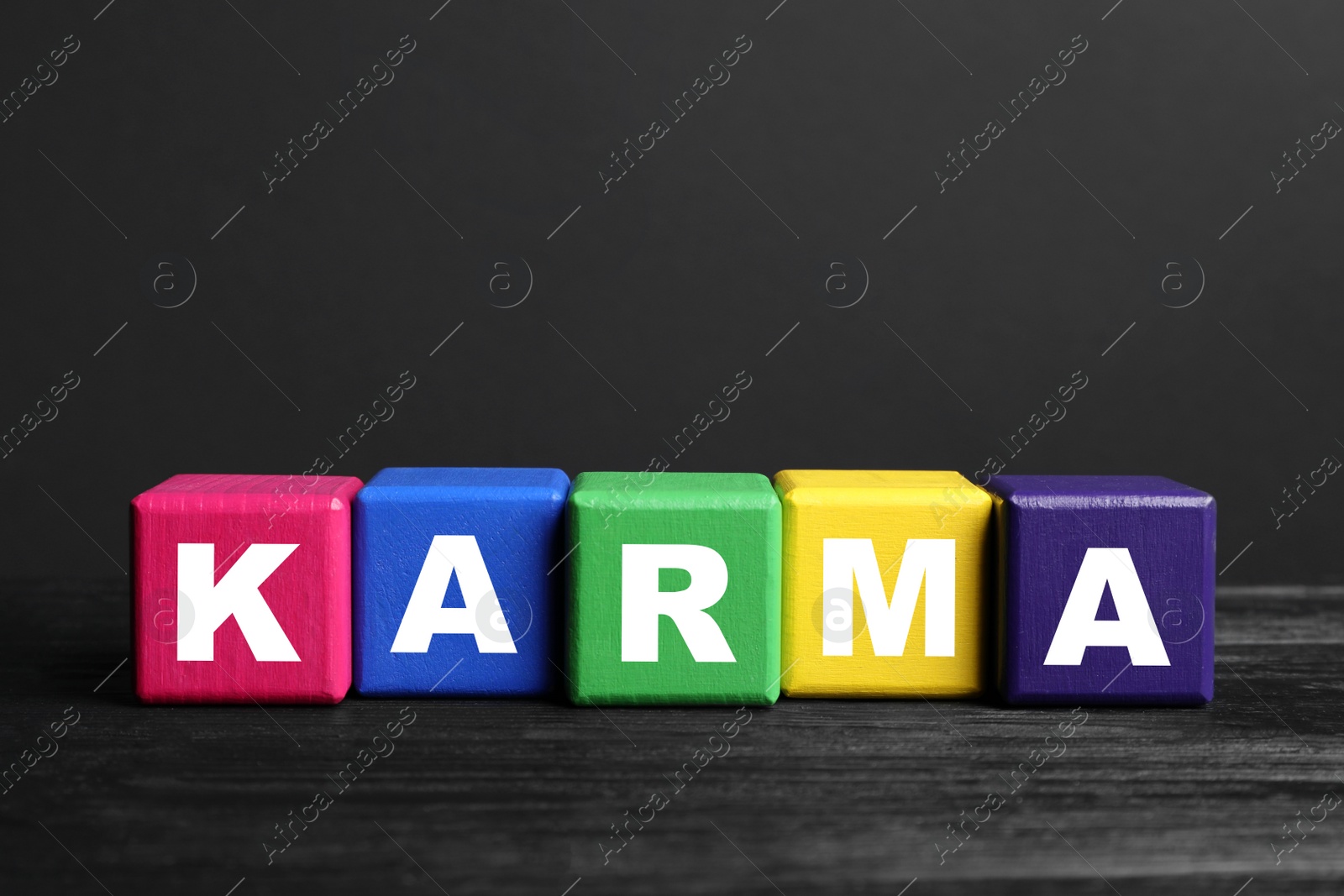 Photo of Word Karma made of colorful cubes with letters on black wooden table