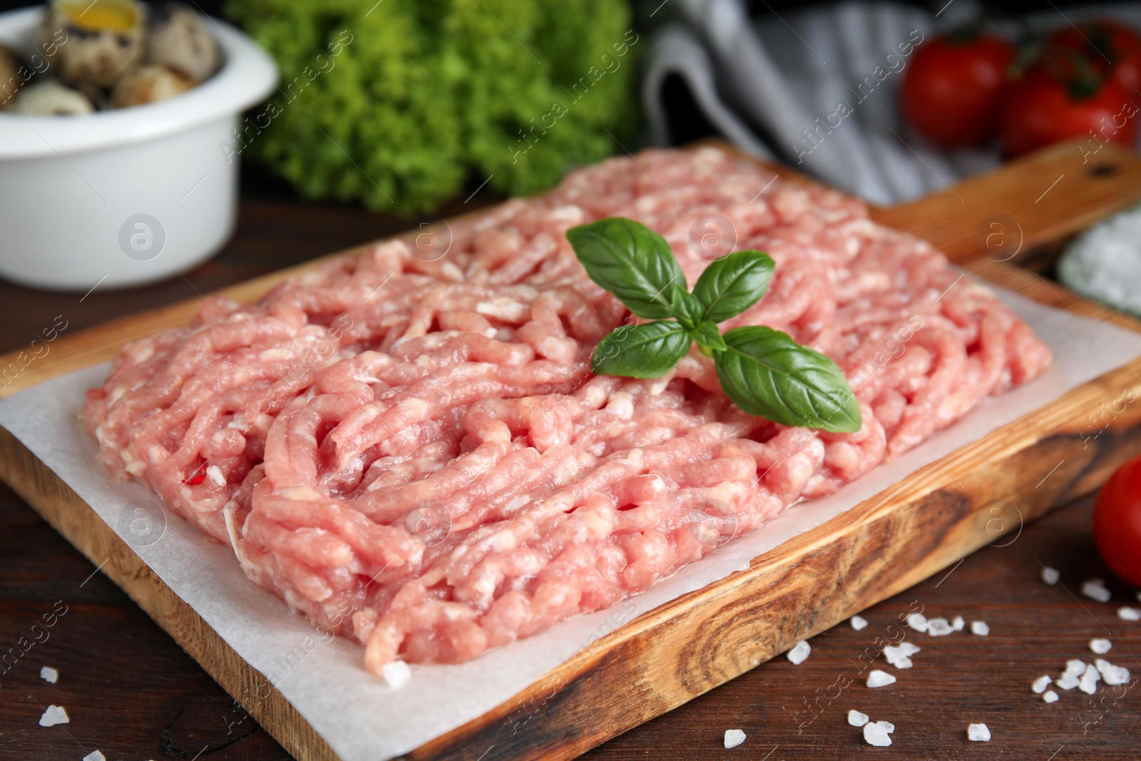 Photo of Raw chicken minced meat with basil and salt on wooden table, closeup