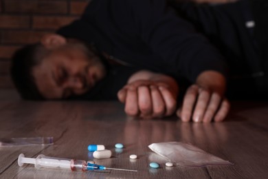 Photo of Overdosed man indoors, focus on different drugs