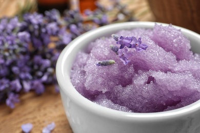 Photo of Bowl of natural sugar scrub and lavender flowers on table, closeup. Space for text