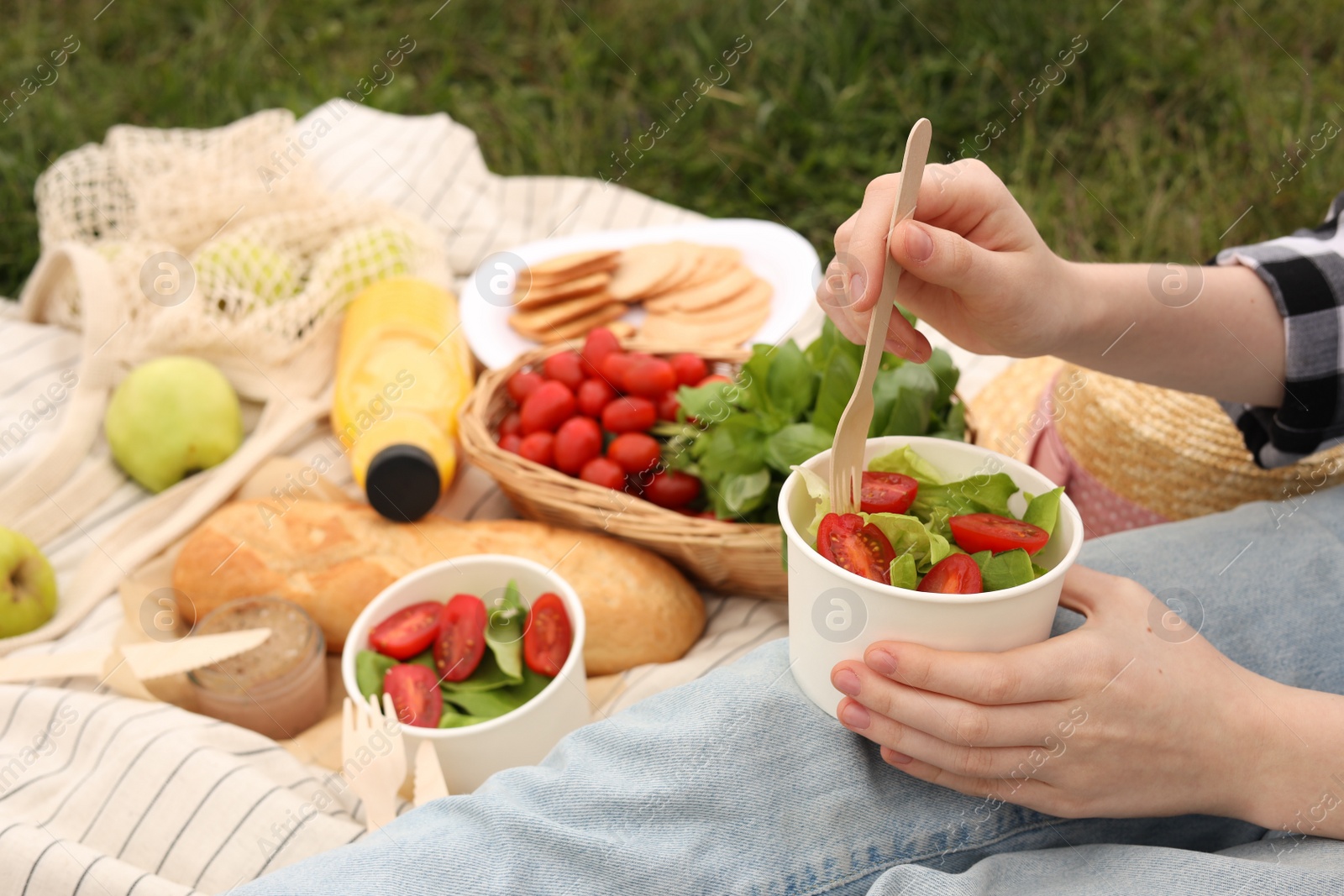 Photo of Girl having picnic on green grass in park, closeup