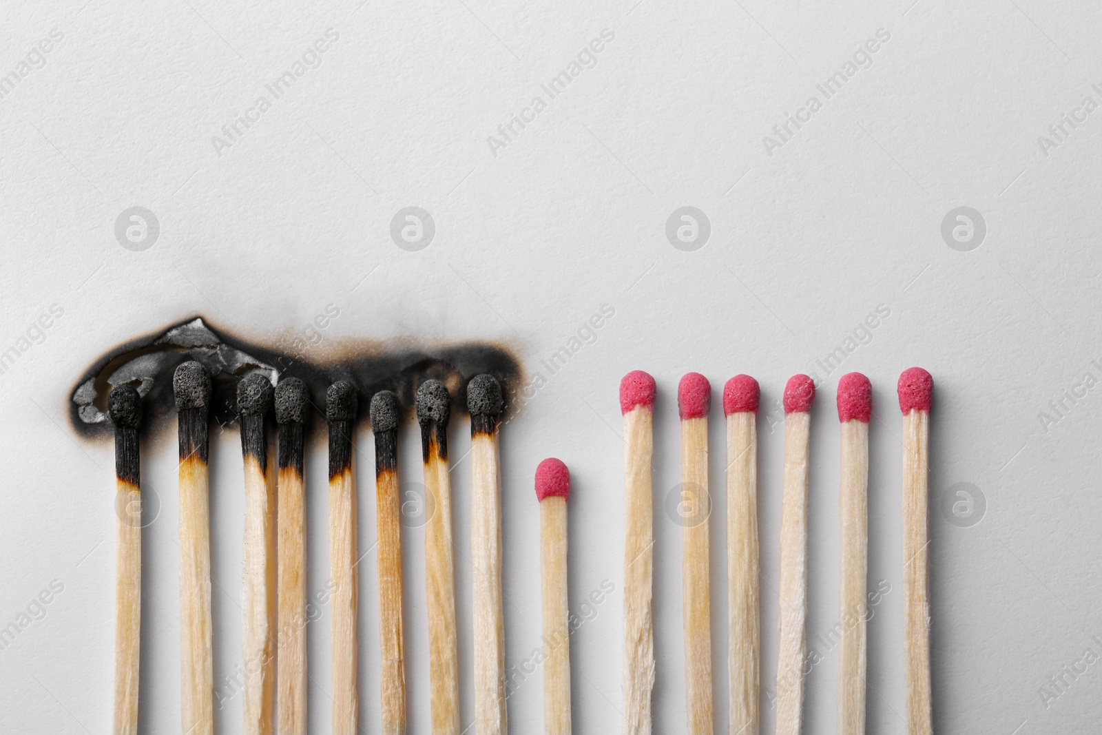 Photo of Burnt and whole matches on white background, flat lay. Space for text