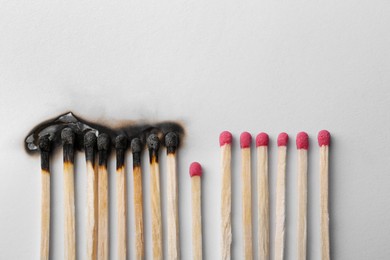 Burnt and whole matches on white background, flat lay. Space for text