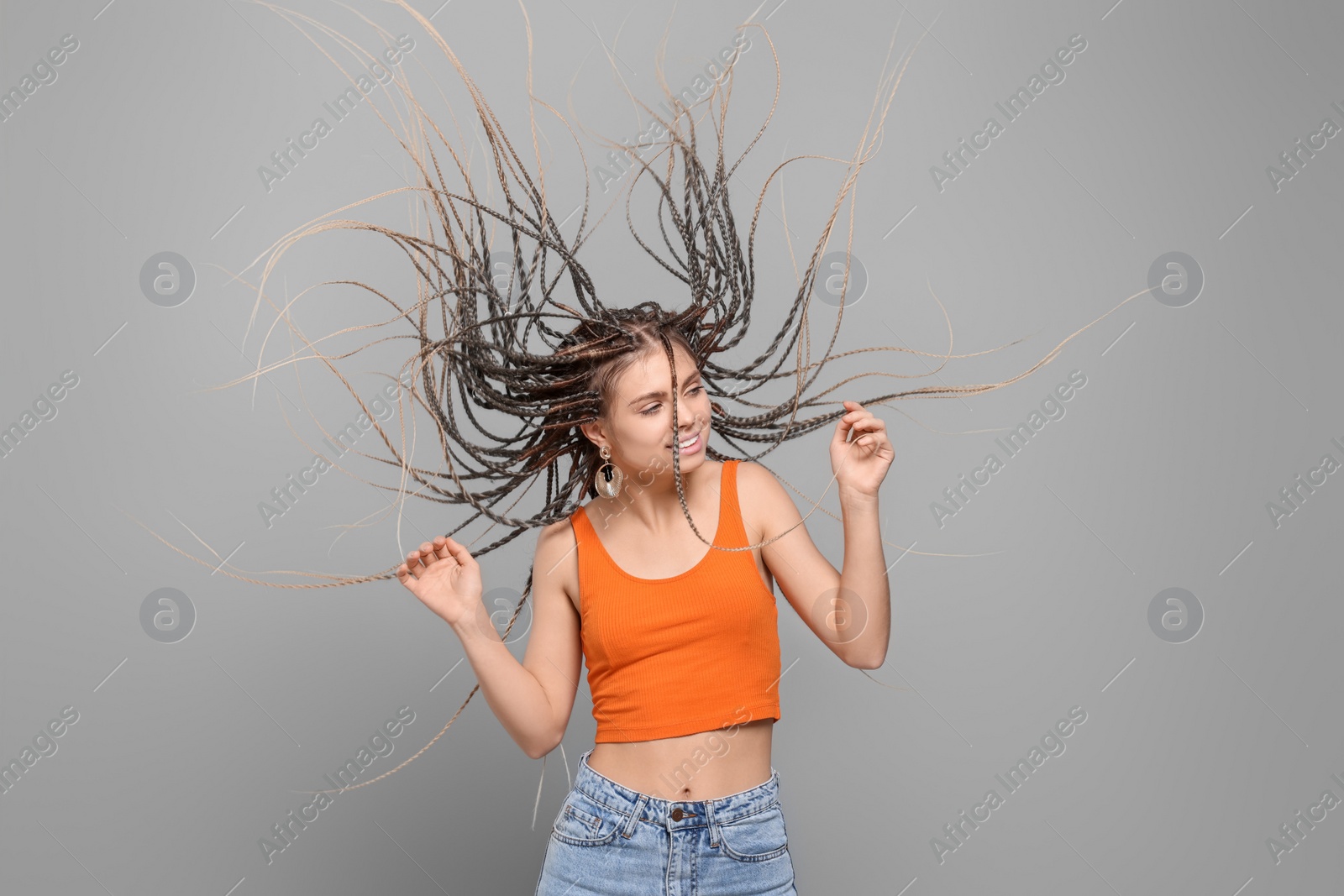 Photo of Beautiful woman with long african braids dancing on grey background