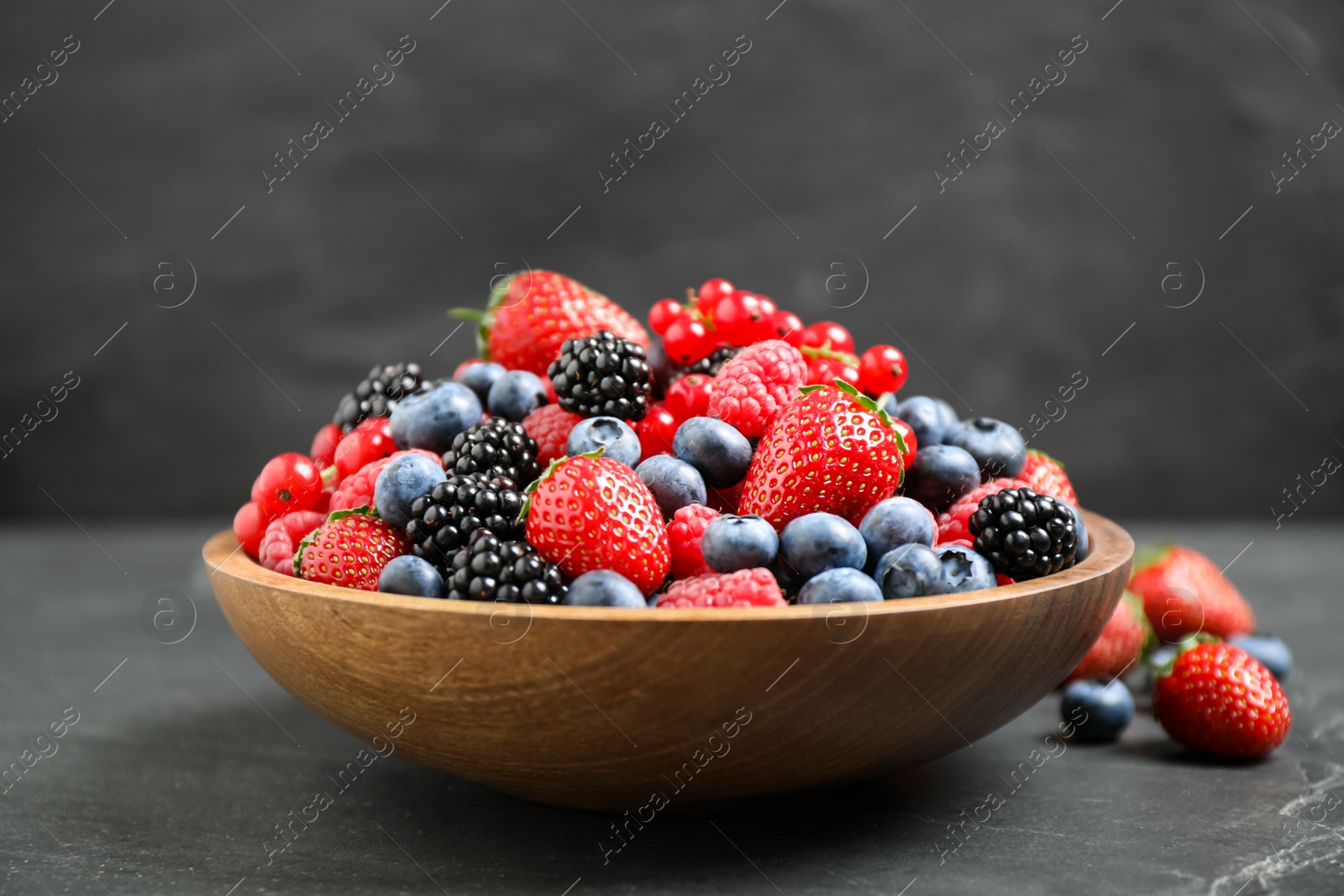 Photo of Mix of different fresh berries in bowl on grey table