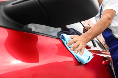 Photo of Man cleaning red auto with duster, closeup. Car wash service