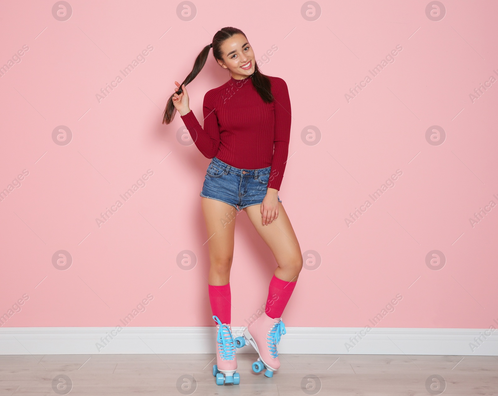 Photo of Young woman with roller skates near color wall