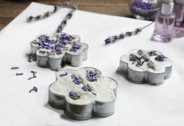 Photo of Handmade soap bars with lavender flowers in metal forms on white paper