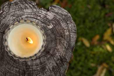 Photo of Burning candle on wooden surface outdoors, top view with space for text. Autumn atmosphere