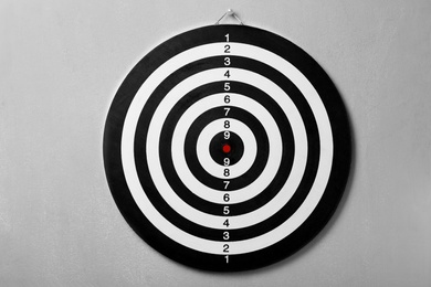 Photo of Dart board hanging on grey concrete wall