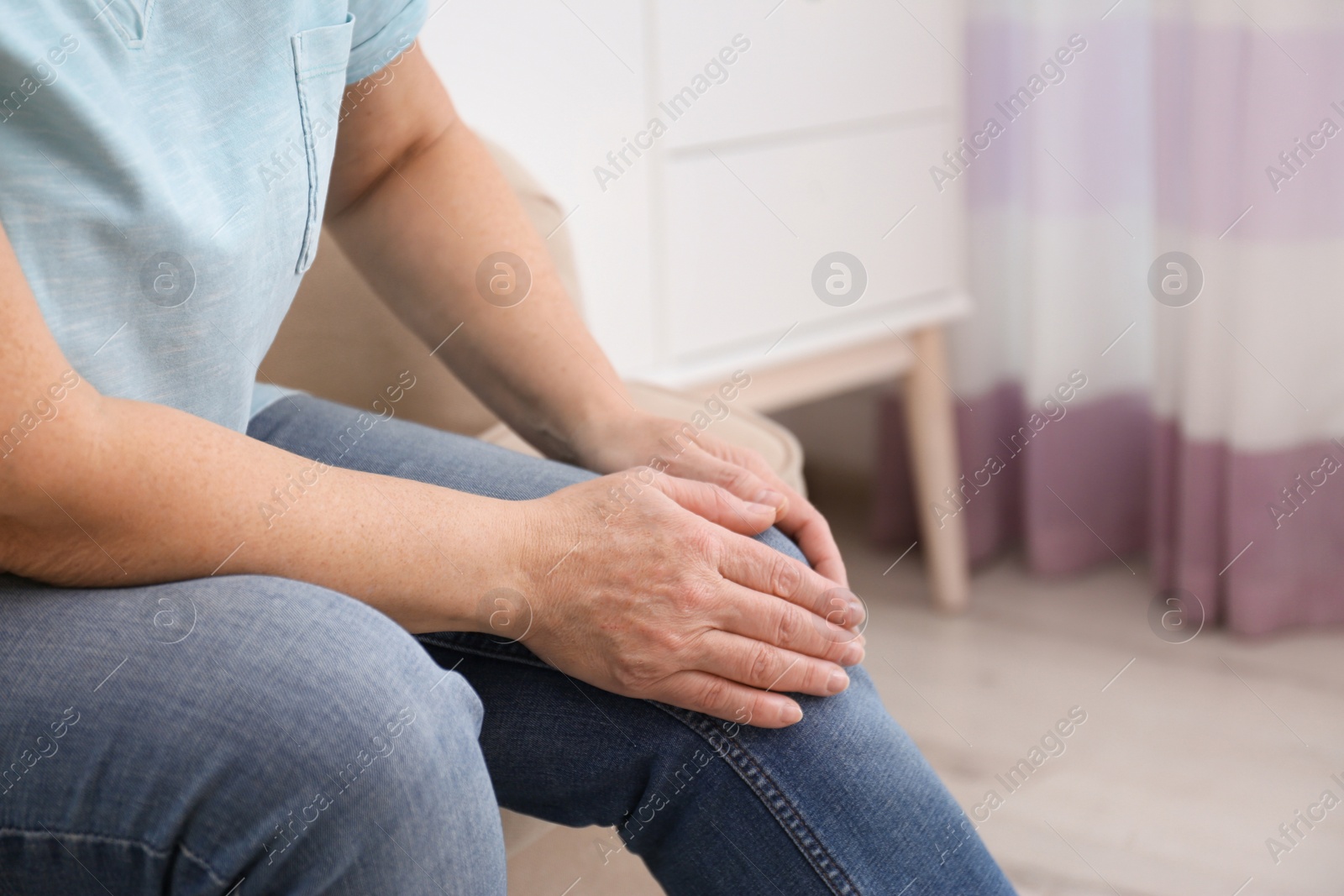 Photo of Senior woman suffering from knee pain at home, closeup. Space for text