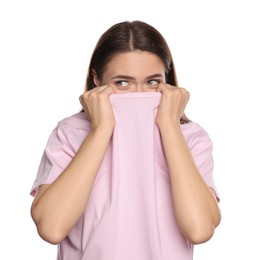 Photo of Embarrassed young woman covering face with shirt on white background