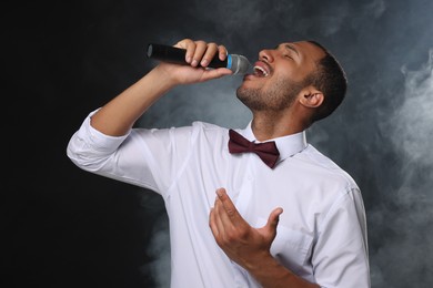Photo of Handsome man with microphone singing on black background