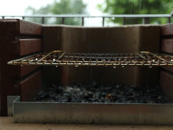 Photo of Empty barbecue grill with grid under rain outdoors, closeup