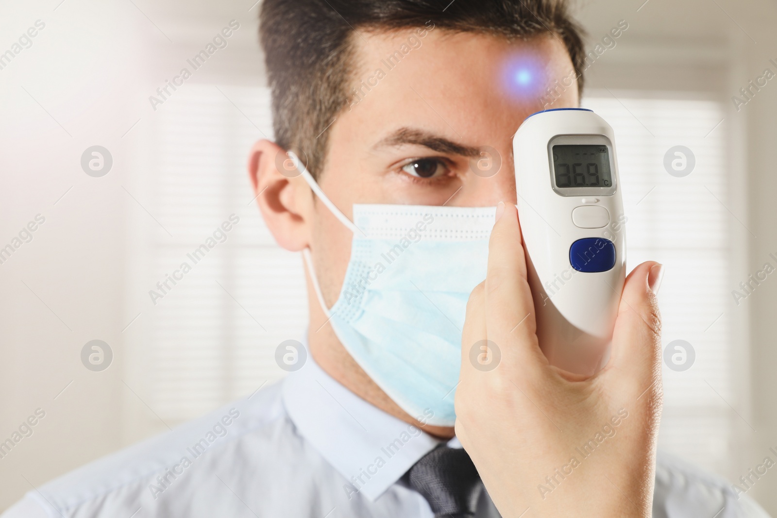 Image of Doctor measuring man's temperature in office closeup. Prevent spreading of Covid-19