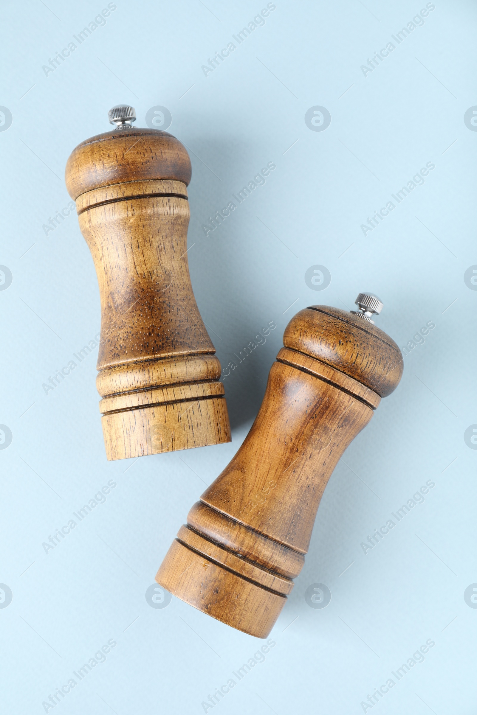 Photo of Wooden salt and pepper shakers on light background, top view