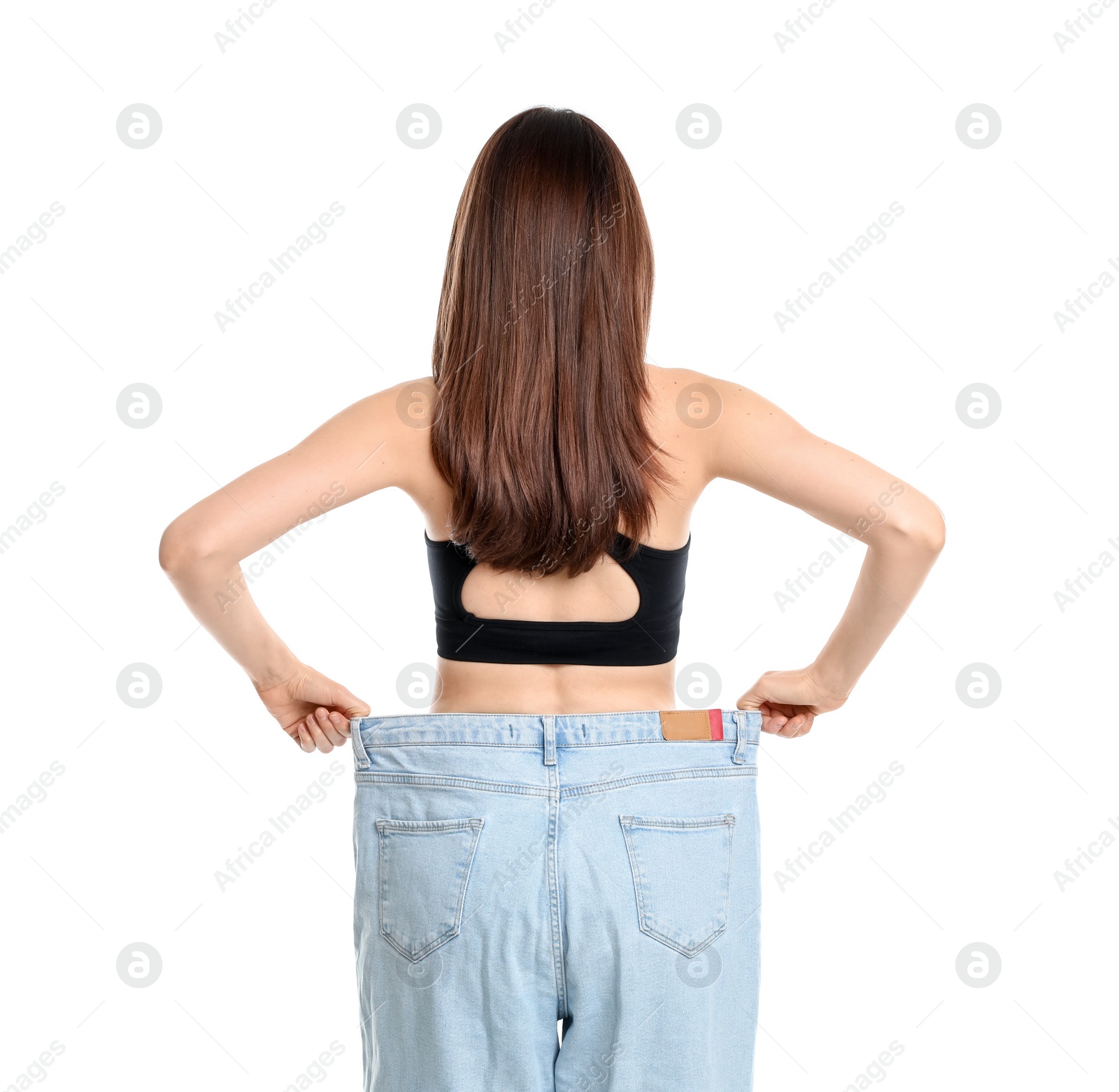 Photo of Woman in big jeans showing her slim body on white background, back view