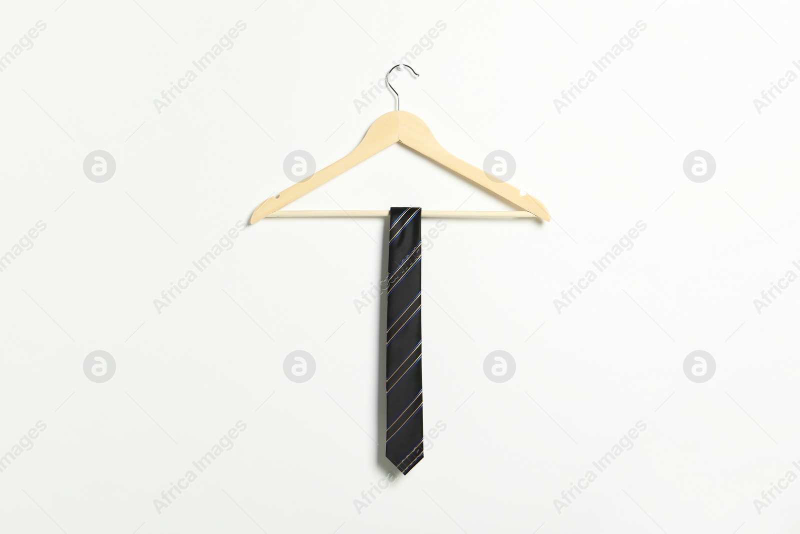Photo of Hanger with striped necktie on white wall
