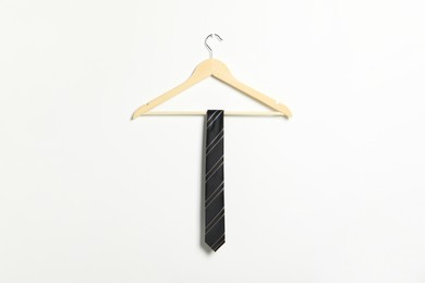 Photo of Hanger with striped necktie on white wall