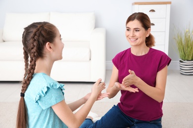 Hearing impaired mother and her child talking with help of sign language indoors