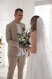 Photo of Happy groom and bride with bouquet indoors. Wedding day