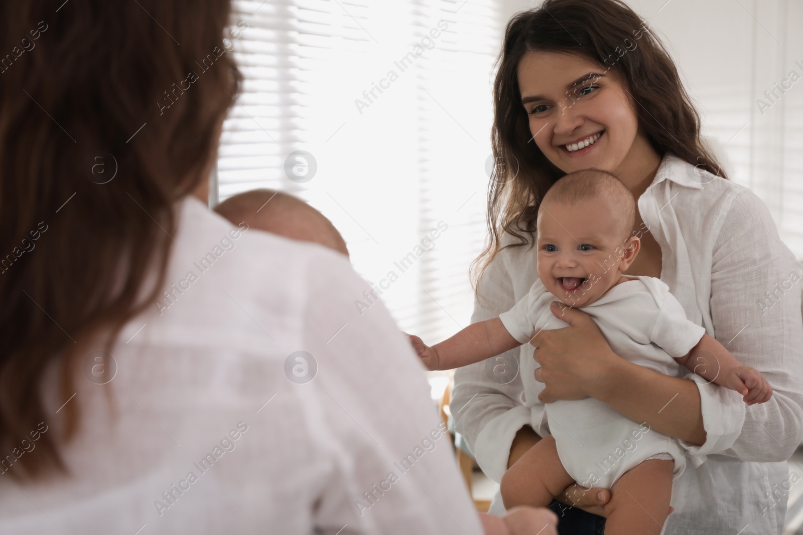 Photo of Happy young mother with her cute baby near mirror at home