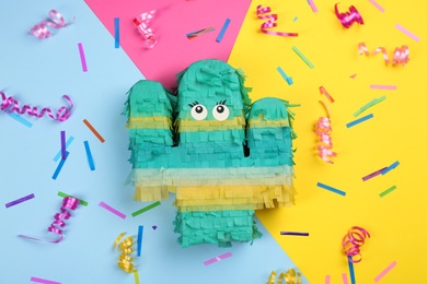 Cactus shaped pinata, streamers and glitter on color background, flat lay
