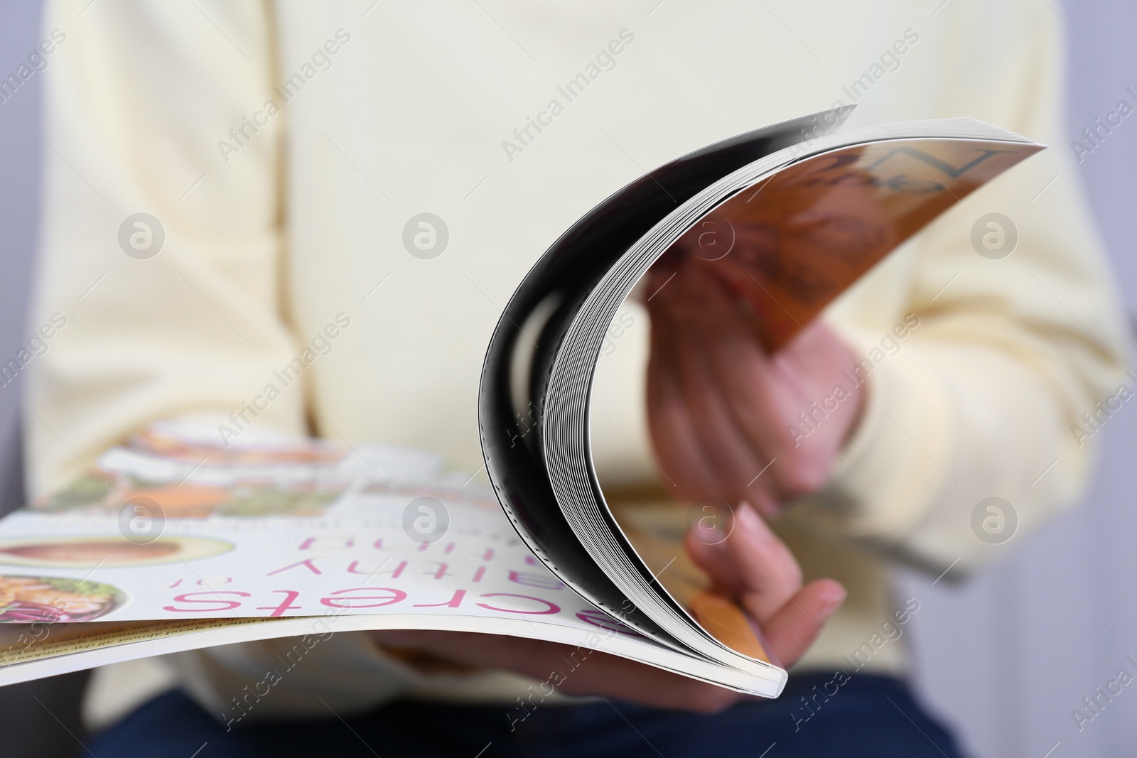 Photo of Woman reading magazine on light grey background, closeup