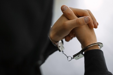 Man detained in handcuffs indoors, closeup view. Criminal law