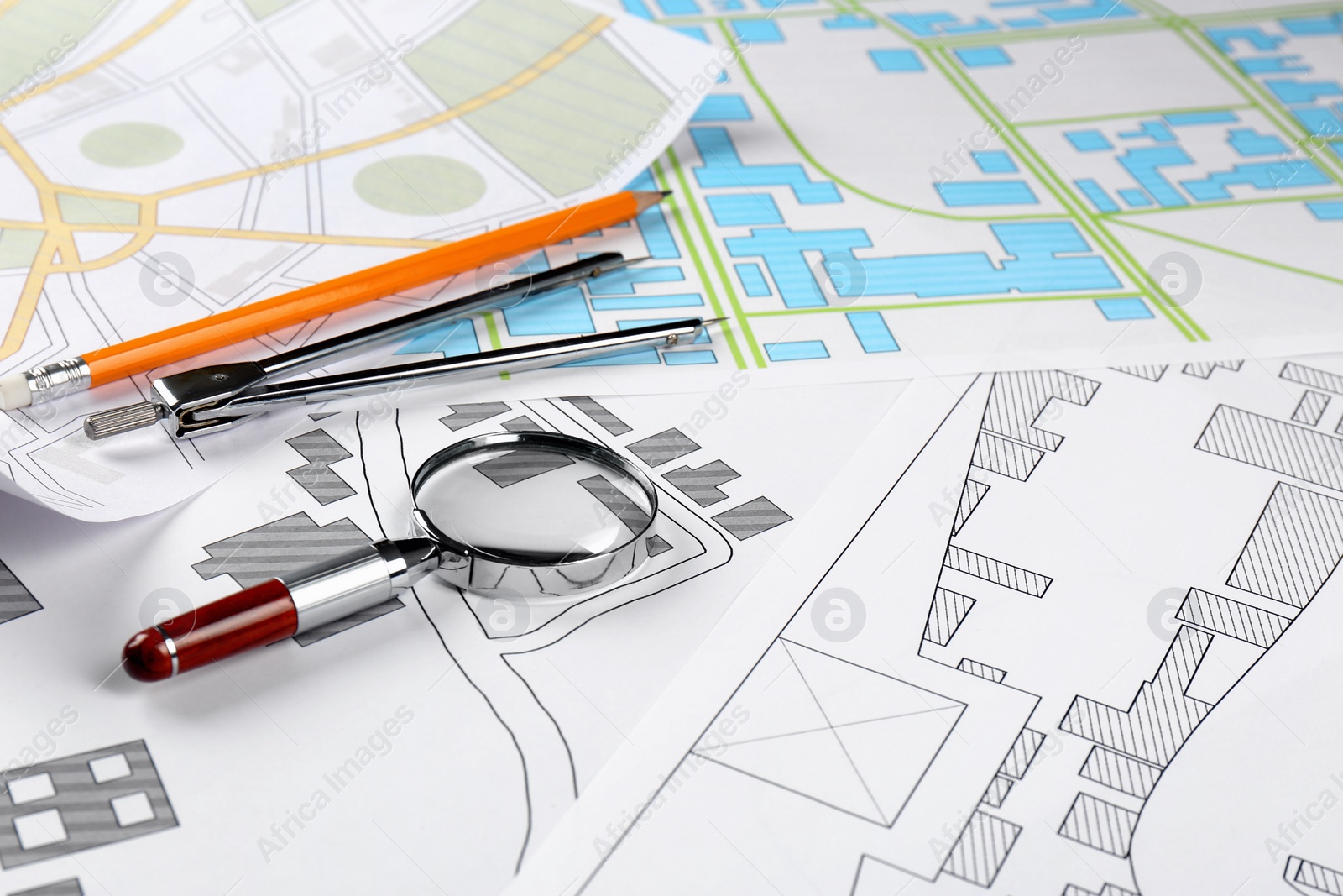 Photo of Office stationery and magnifying glass on cadastral maps of territory with buildings