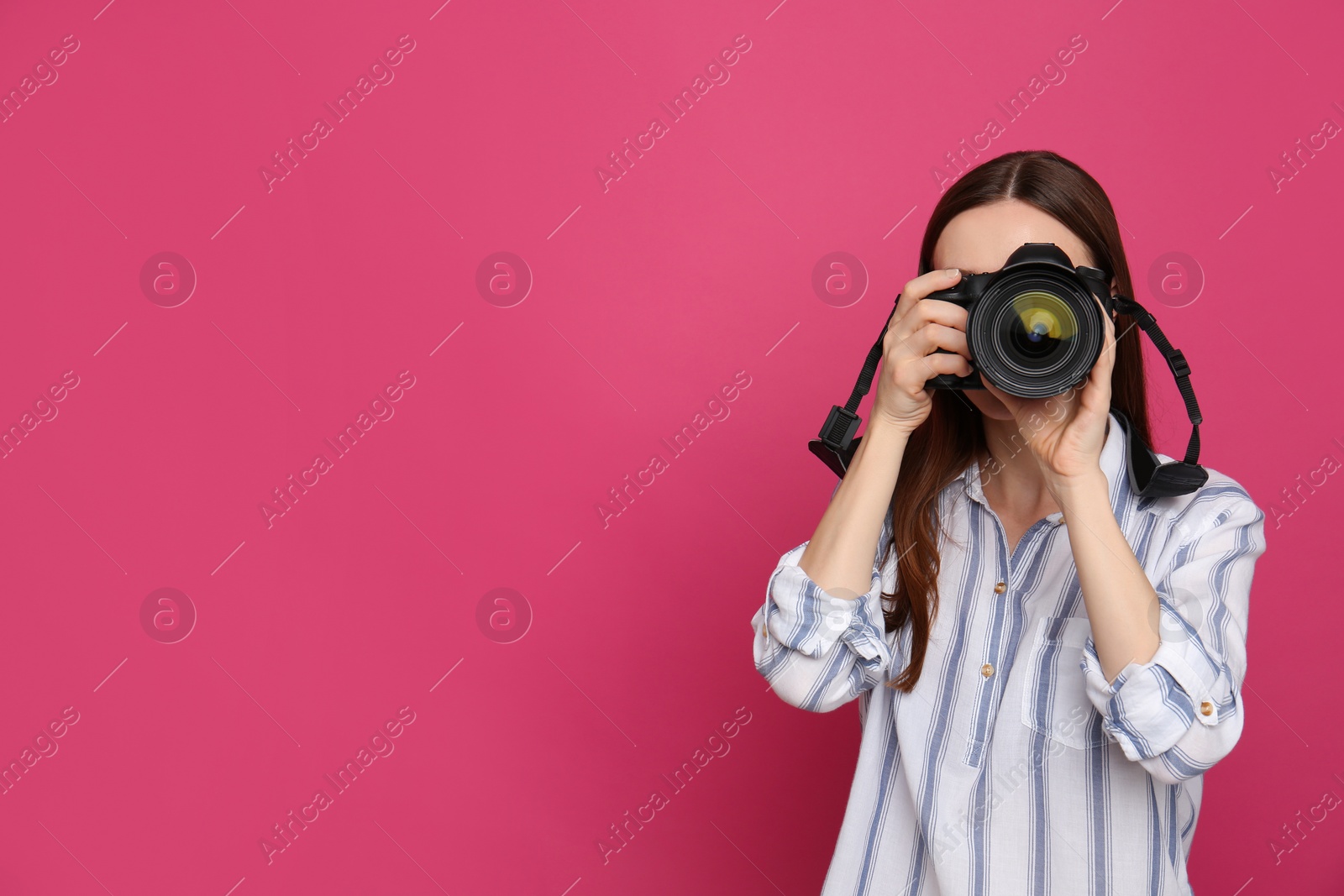 Photo of Professional photographer taking picture on pink background. Space for text