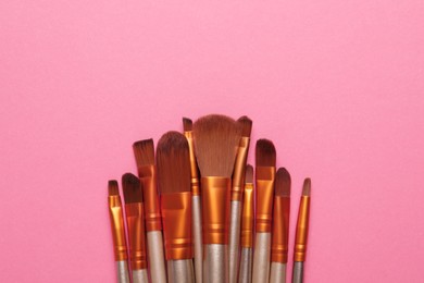 Photo of Set of makeup brushes on pink background, flat lay. Space for text