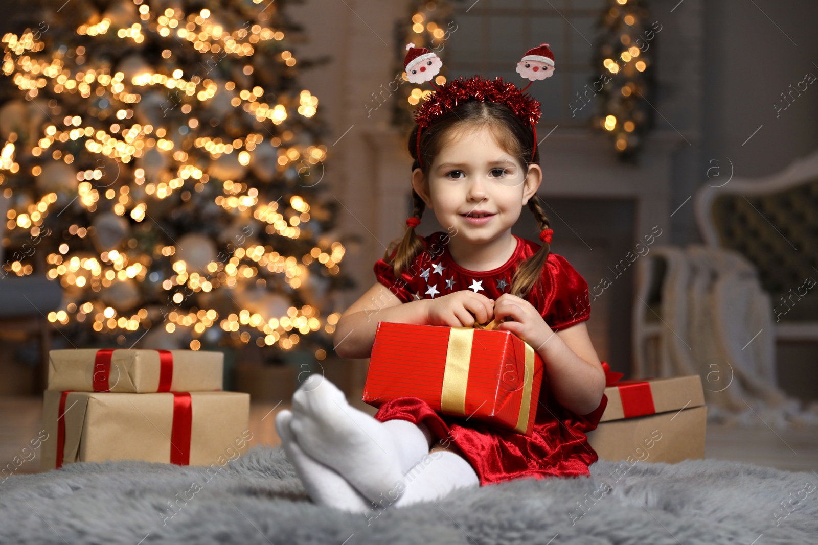 Photo of Cute little child with Christmas gift in living room