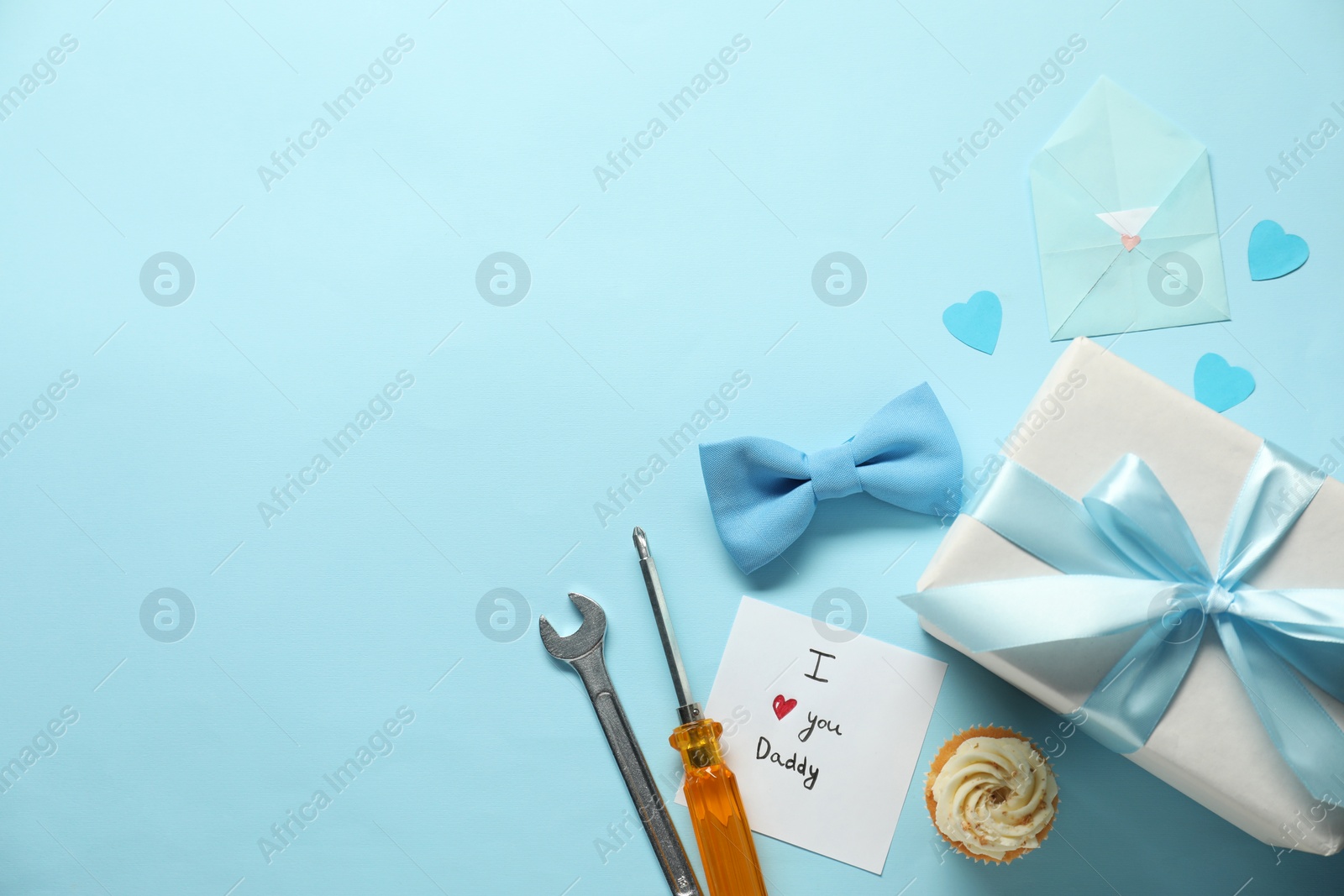 Photo of Gift box, cupcake and men accessories on light blue background, flat lay with space for text. Father's day celebration