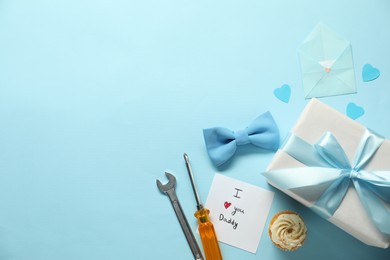 Photo of Gift box, cupcake and men accessories on light blue background, flat lay with space for text. Father's day celebration