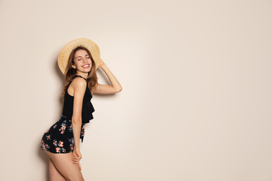 Photo of Young woman wearing floral print shorts and straw hat on beige background. Space for text