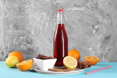 Bottle of aromatic punch drink and ingredients on light blue table