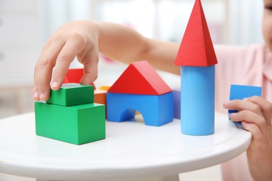 Photo of Cute child playing with colorful blocks at home, closeup