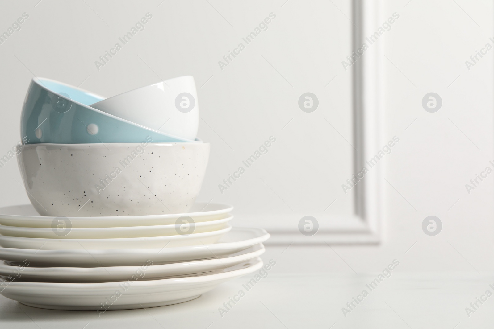 Photo of Stack of beautiful ceramic dishware on white table, space for text