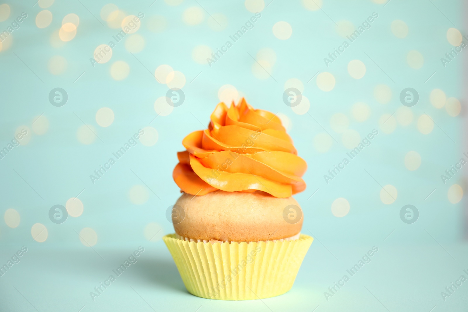 Photo of Beautiful cupcake on light blue background with blurred lights. Birthday treat