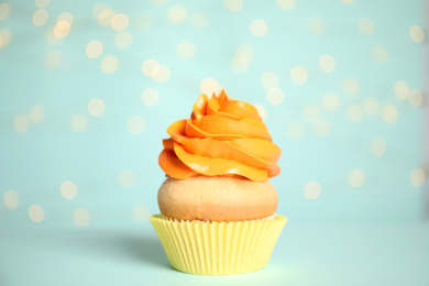 Photo of Beautiful cupcake on light blue background with blurred lights. Birthday treat