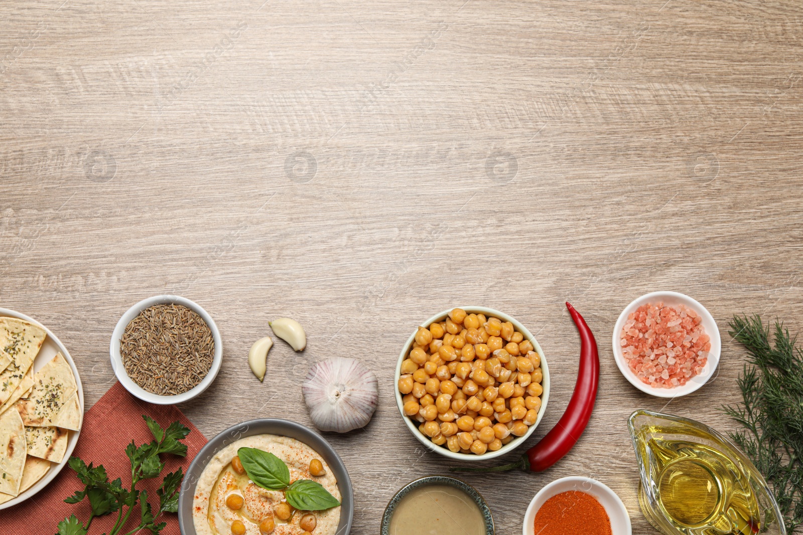 Photo of Many different ingredients on wooden table, flat lay with space for text. Cooking delicious hummus