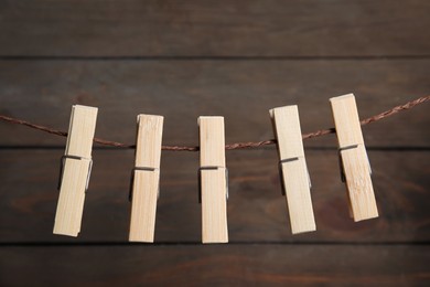 Photo of Many clothespins on rope against wooden background