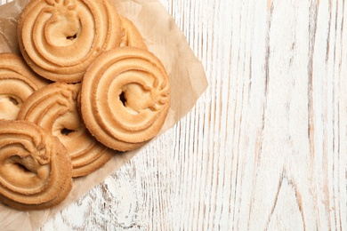 Photo of Tasty Danish butter cookies on wooden background, top view with space for text