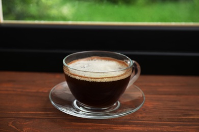 Cup of hot coffee on wooden windowsill