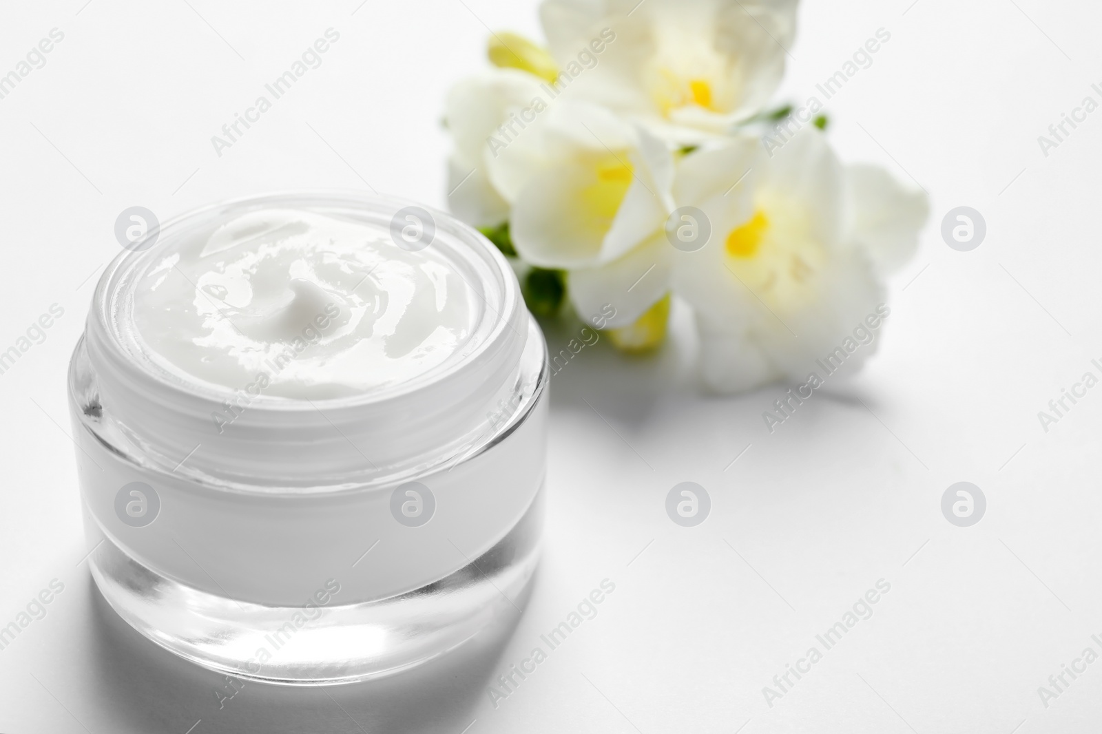 Photo of Jar of cream and flowers on white background. Professional cosmetic products